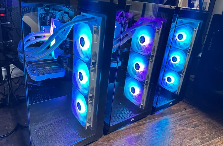 Three desktop PC towers side by side with blue and purple illuminated fans